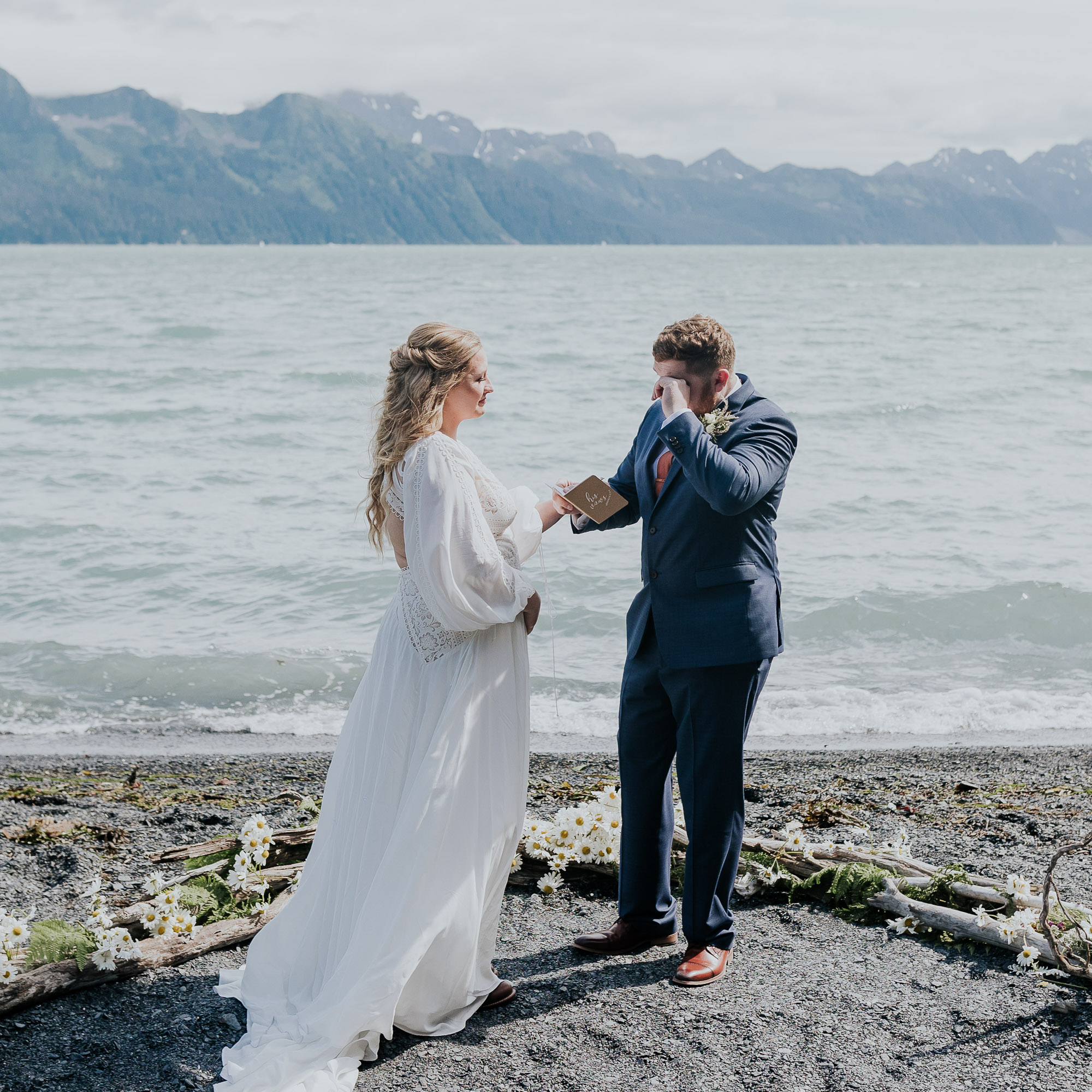 emotional groom reading vows to bride on sunny seward alaska beach